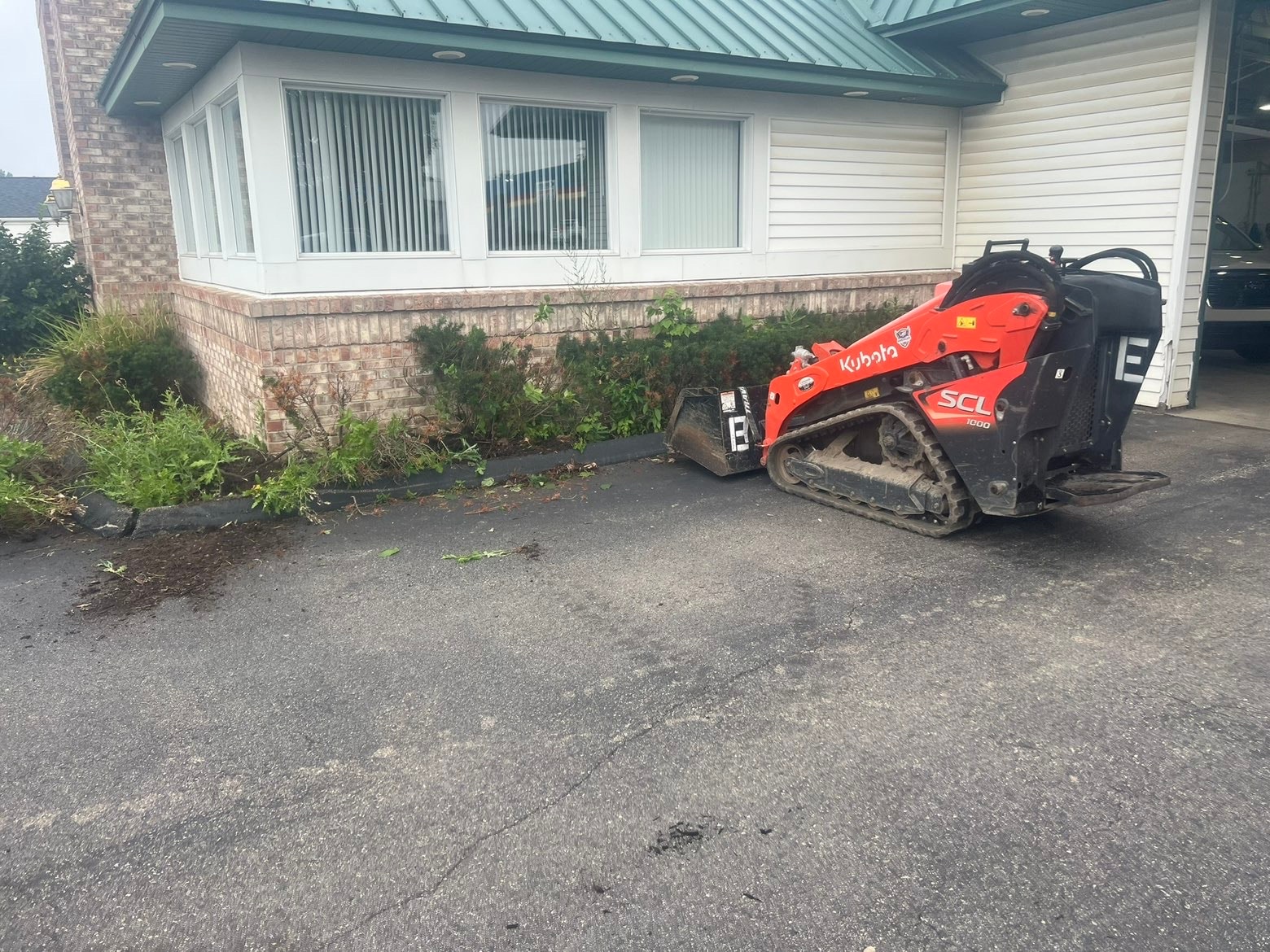 Kubota track loader removing shrubs during commercial hardscape project — Bemis