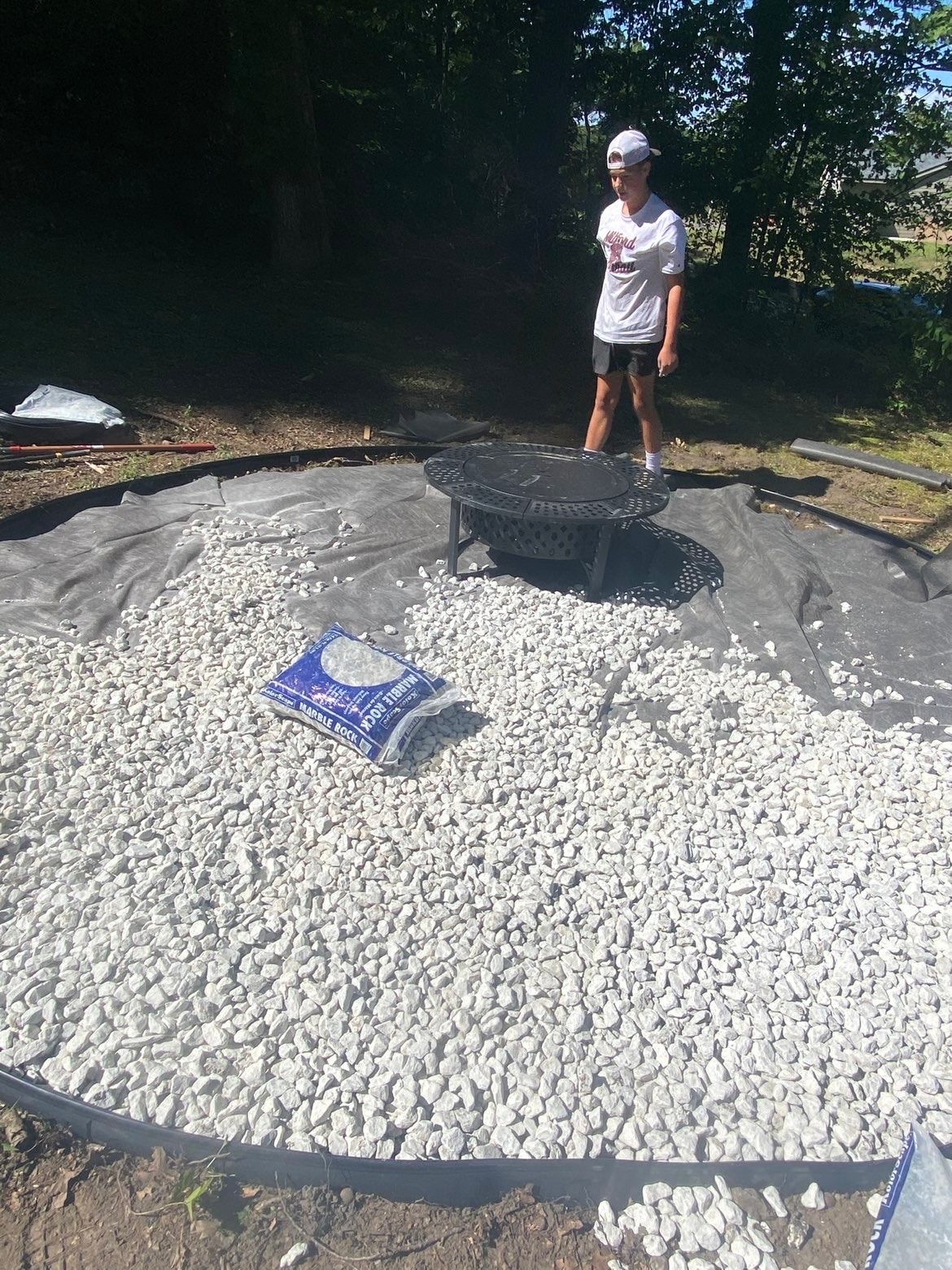 Fire pit area with marble rock and landscape fabric installed — Bemis
