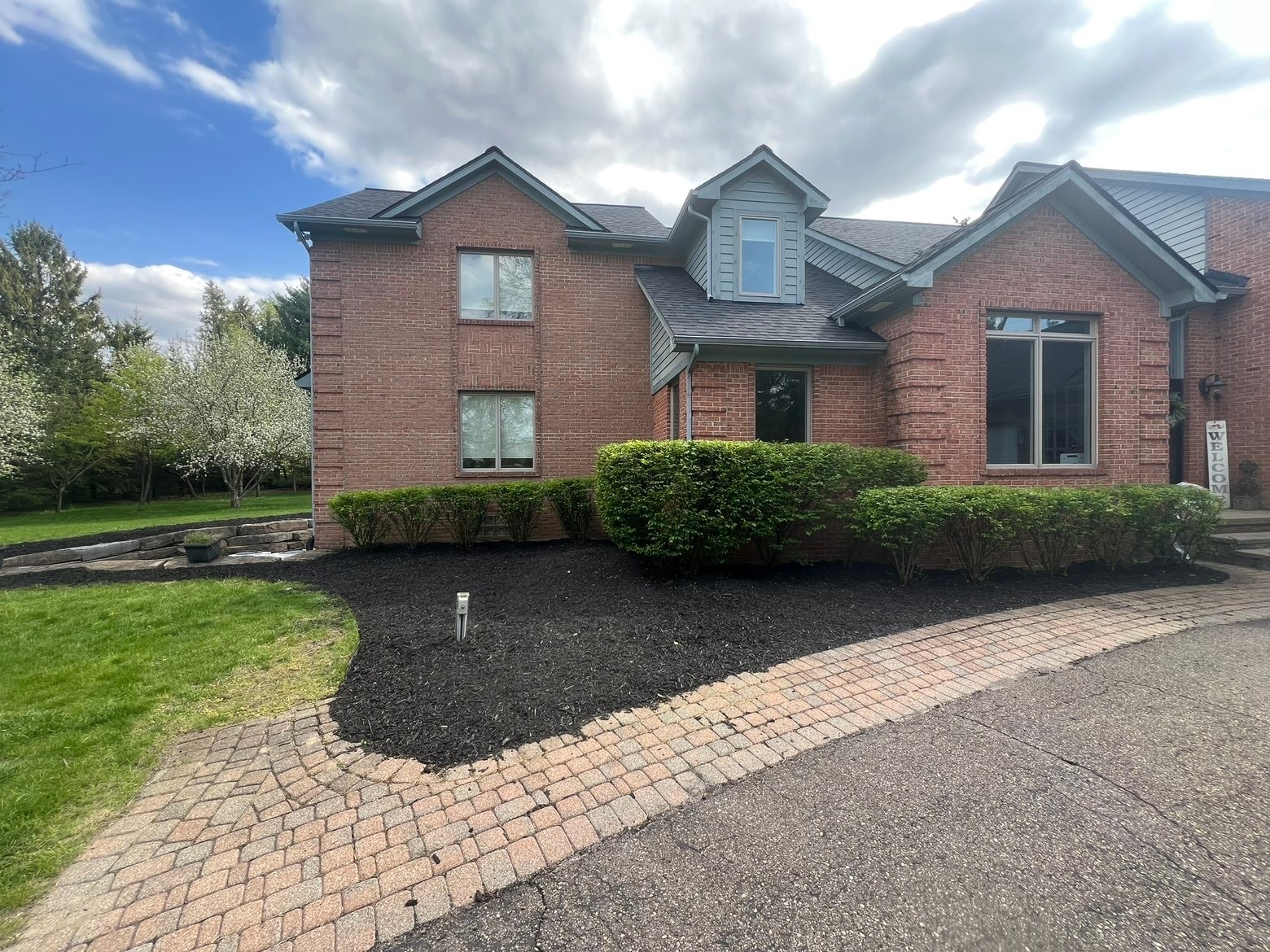Brick house with manicured landscaping and driveway — Bemis