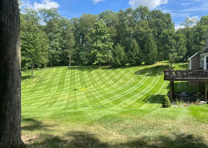 Bemis Lawn & Landscape crew mowing a residential property